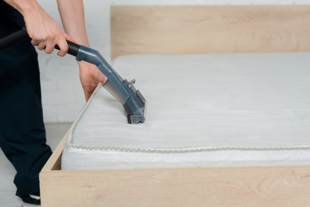 person vacuuming a mattress